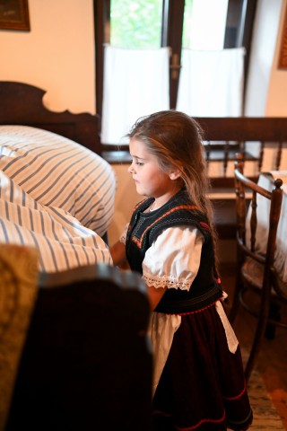 Népviseletbe öltözött kislány az ágyat is megvetette. A fotót a Z'imázs Foto készítette.