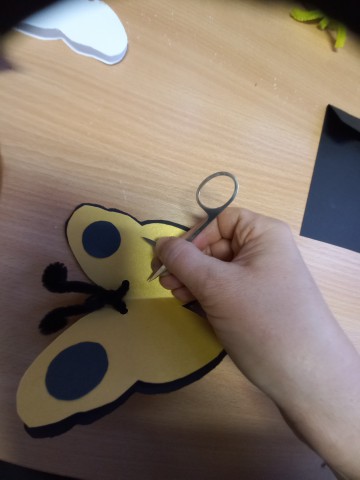 A szárny szélein, középen apró lyukat készítünk az olló hegyével. A lyukakba damilt fűzünk.